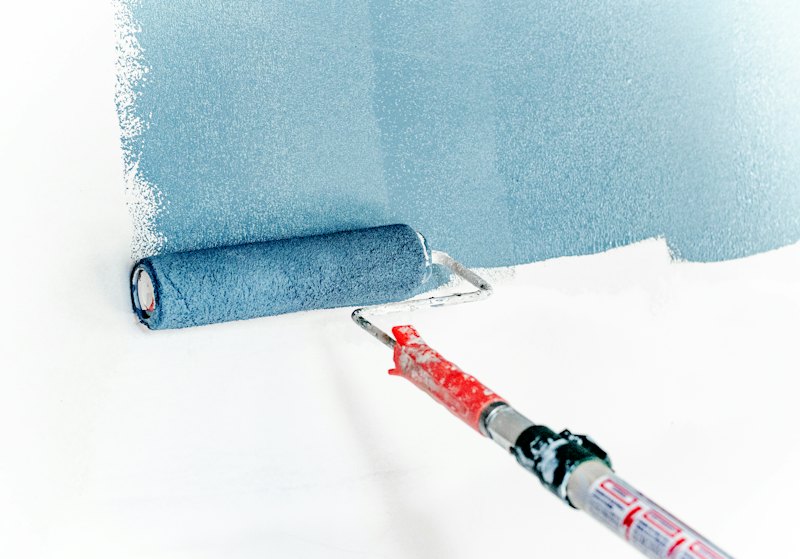 A paint roller putting a fresh coat on a wall