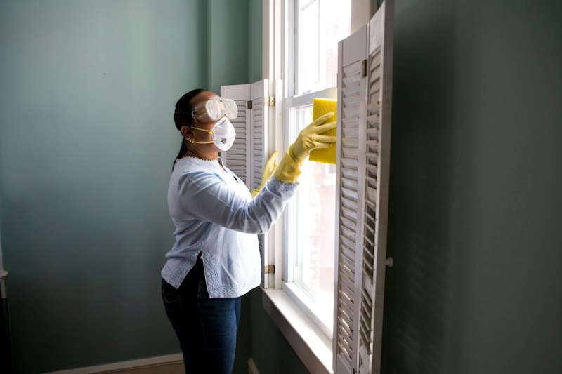 Someone cleaning a window and shutter indoors